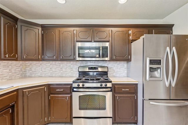 316 SE 6th St, Moore, OK 73160 - kitchen featuring appliances with stainless steel finishes, light countertops, backsplash, dark brown cabinetry, and a textured ceiling