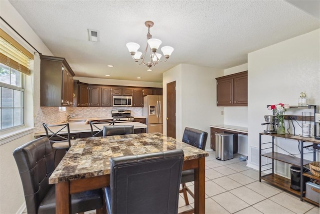 316 SE 6th St, Moore, OK 73160 - dining area featuring a chandelier, light tile patterned floors, a textured ceiling, and baseboards