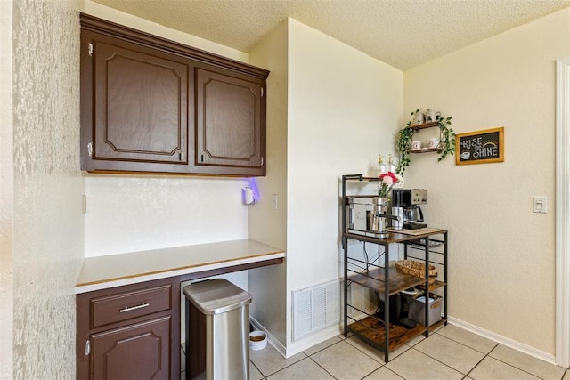 316 SE 6th St, Moore, OK 73160 - kitchen with light tile patterned flooring, baseboards, a textured ceiling, light countertops, and dark brown cabinets