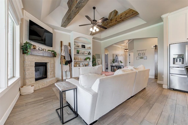 12004 SW 49th St, Mustang, OK 73064 - living area with a ceiling fan, a stone fireplace, baseboards, arched walkways, and beam ceiling