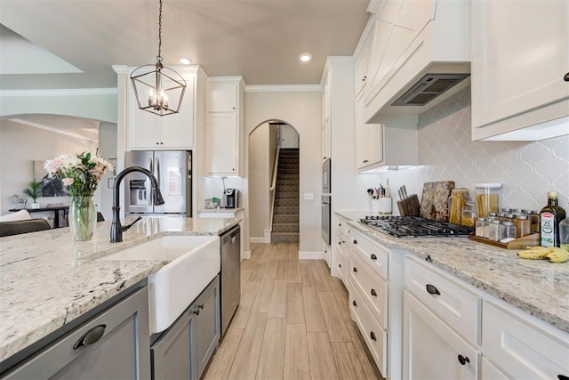 12004 SW 49th St, Mustang, OK 73064 - kitchen with arched walkways, a sink, stainless steel appliances, ornamental molding, and white cabinets