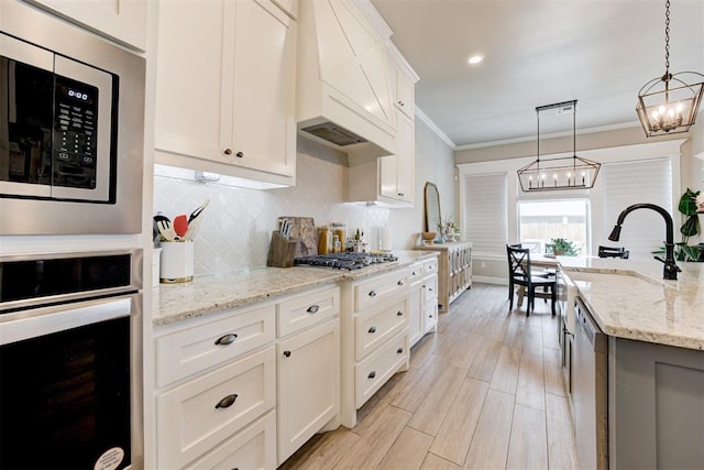12004 SW 49th St, Mustang, OK 73064 - kitchen with appliances with stainless steel finishes, a chandelier, premium range hood, decorative backsplash, and light stone countertops