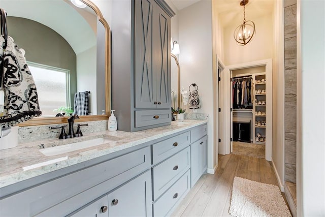 12004 SW 49th St, Mustang, OK 73064 - bathroom with double vanity, a walk in closet, wood finished floors, and a chandelier