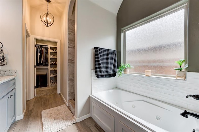 12004 SW 49th St, Mustang, OK 73064 - full bathroom featuring wood finished floors, a whirlpool tub, a spacious closet, vanity, and walk in shower