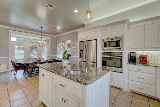16523 Roserock Cir, Choctaw, OK 73020 - kitchen with appliances with stainless steel finishes, light tile patterned floors, an island with sink, crown molding, and dark stone counters