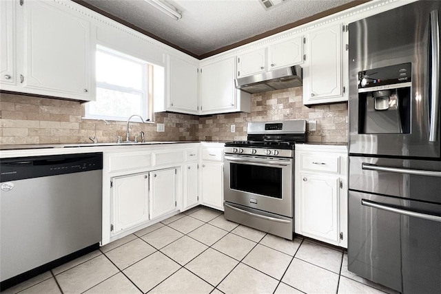 8409 Bigwood Dr, Oklahoma City, OK 73135 - kitchen featuring appliances with stainless steel finishes, under cabinet range hood, light tile patterned floors, white cabinetry, and decorative backsplash