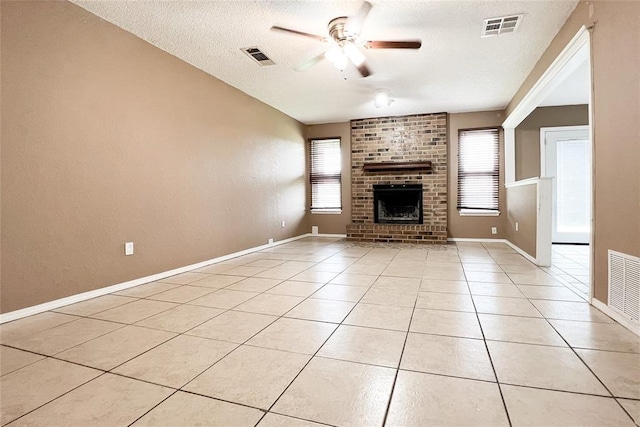 8409 Bigwood Dr, Oklahoma City, OK 73135 - unfurnished living room featuring ceiling fan, a textured ceiling, a brick fireplace, light tile patterned floors, and baseboards
