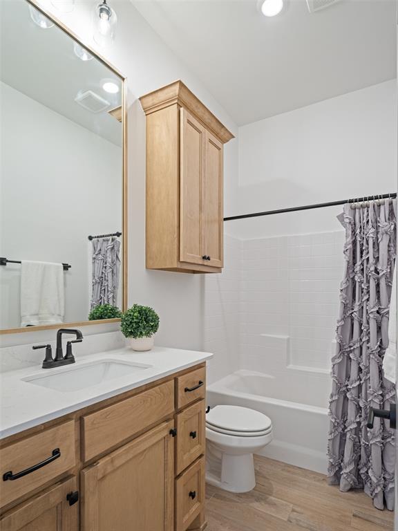 7909 NW 162nd St, Edmond, OK 73013 - full bathroom with vanity, wood finished floors, toilet, and shower / bath combo with shower curtain