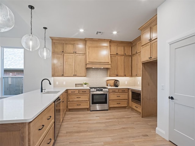 7909 NW 162nd St, Edmond, OK 73013 - kitchen featuring appliances with stainless steel finishes, a sink, a peninsula, light wood-style floors, and backsplash