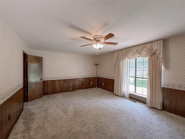 715 N Max, Hinton, OK 73047 - carpeted empty room featuring wallpapered walls, a wainscoted wall, wooden walls, and a ceiling fan
