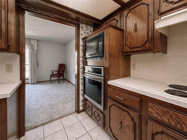 715 N Max, Hinton, OK 73047 - kitchen featuring stainless steel oven, light countertops, light carpet, a textured ceiling, and under cabinet range hood