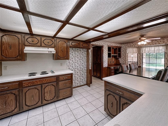 715 N Max, Hinton, OK 73047 - kitchen featuring under cabinet range hood, wallpapered walls, light countertops, white electric cooktop, and a textured ceiling