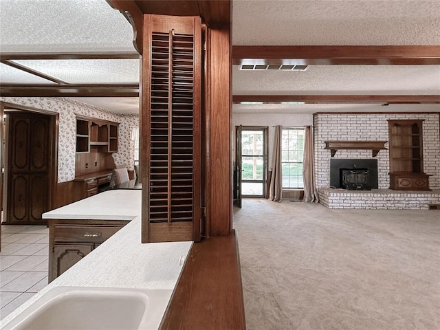 715 N Max, Hinton, OK 73047 - kitchen featuring wallpapered walls, beam ceiling, a textured ceiling, light countertops, and light carpet