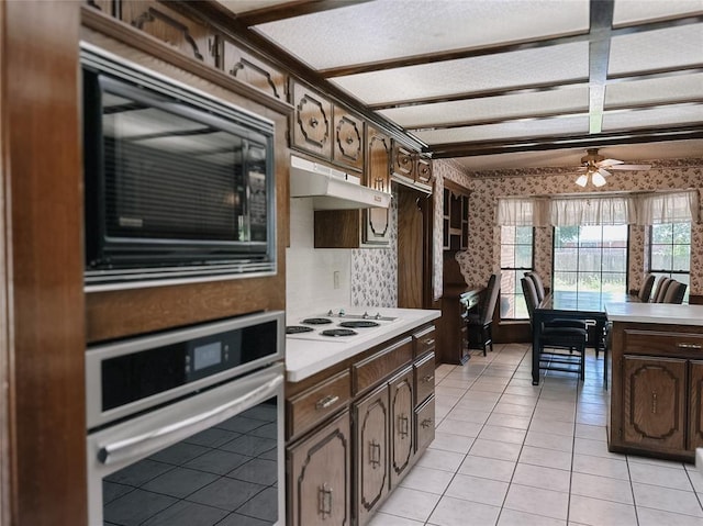 715 N Max, Hinton, OK 73047 - kitchen with stainless steel oven, black microwave, wallpapered walls, light countertops, and white electric cooktop