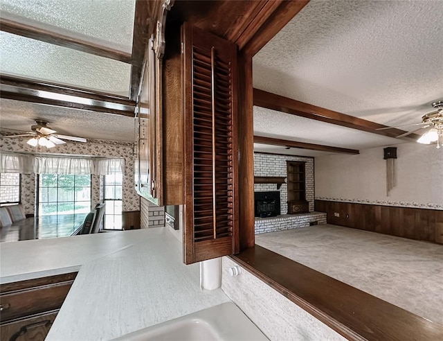 715 N Max, Hinton, OK 73047 - unfurnished living room featuring ceiling fan, a textured ceiling, wainscoting, carpet flooring, and a brick fireplace