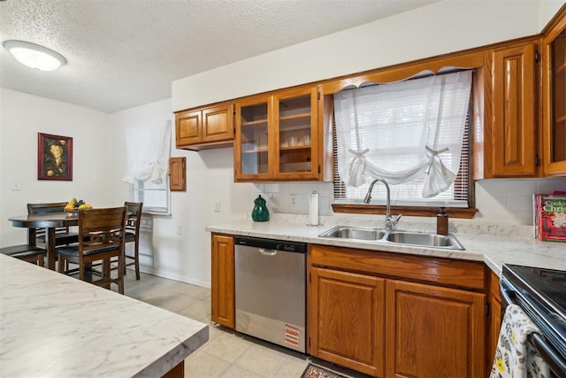 3831 NW Bell Ave, Lawton, OK 73505 - kitchen with stainless steel dishwasher, a sink, light countertops, brown cabinetry, and glass insert cabinets