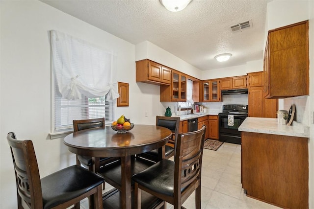 3831 NW Bell Ave, Lawton, OK 73505 - kitchen featuring black range with electric cooktop, a sink, under cabinet range hood, brown cabinetry, and a textured ceiling