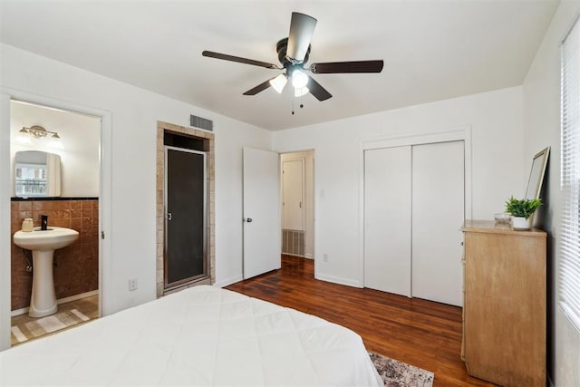 3831 NW Bell Ave, Lawton, OK 73505 - bedroom with wood finished floors, ensuite bath, tile walls, a sink, and ceiling fan