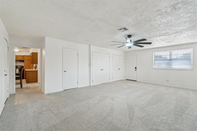 3831 NW Bell Ave, Lawton, OK 73505 - unfurnished bedroom with two closets, light carpet, baseboards, a textured ceiling, and ceiling fan