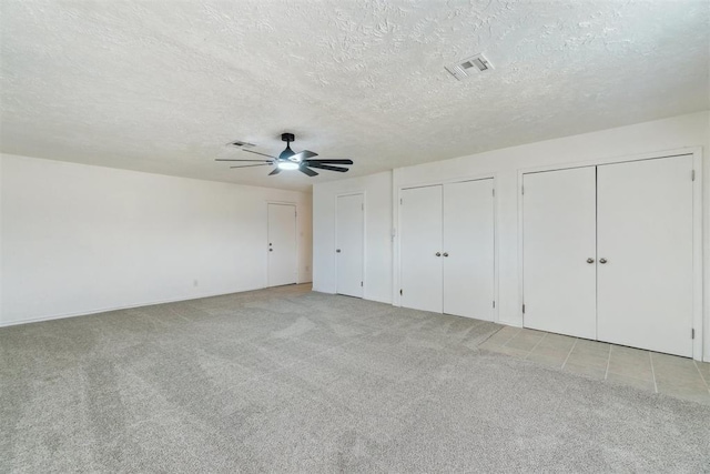 3831 NW Bell Ave, Lawton, OK 73505 - unfurnished bedroom with light carpet, a textured ceiling, two closets, ceiling fan, and baseboards