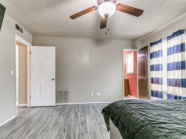 216 N English Dr, Moore, OK 73160 - bedroom featuring wood finished floors, a textured ceiling, baseboards, a ceiling fan, and ensuite bath