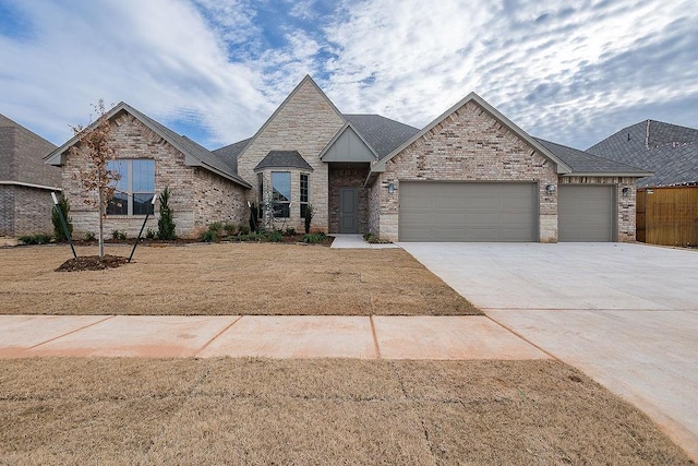 9120 SW 34th St, Oklahoma City, OK 73179 - french provincial home featuring a garage, concrete driveway, and stone siding