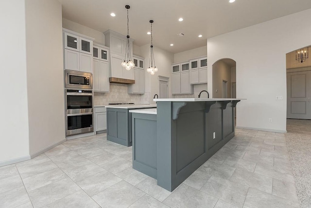 9120 SW 34th St, Oklahoma City, OK 73179 - kitchen with appliances with stainless steel finishes, a large island, tasteful backsplash, light countertops, and baseboards