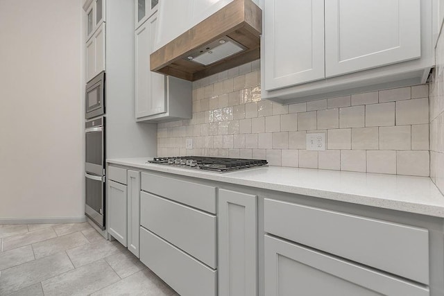 9120 SW 34th St, Oklahoma City, OK 73179 - kitchen featuring custom exhaust hood, stainless steel appliances, decorative backsplash, baseboards, and glass insert cabinets