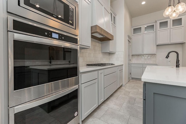 9120 SW 34th St, Oklahoma City, OK 73179 - kitchen with stainless steel appliances, tasteful backsplash, a sink, hanging light fixtures, and glass insert cabinets