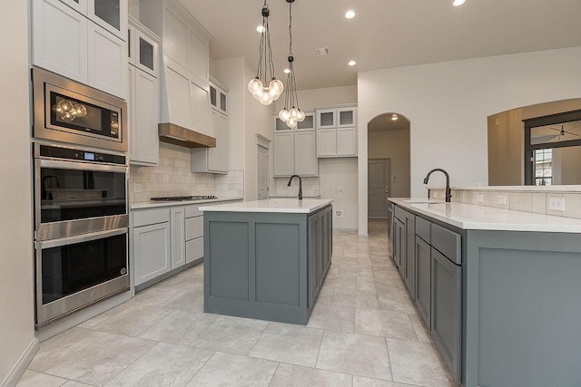9120 SW 34th St, Oklahoma City, OK 73179 - kitchen featuring gray cabinetry, an island with sink, appliances with stainless steel finishes, a sink, and decorative backsplash