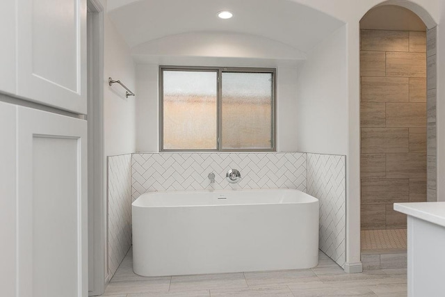 9120 SW 34th St, Oklahoma City, OK 73179 - bathroom featuring tile walls, a freestanding bath, and a wainscoted wall