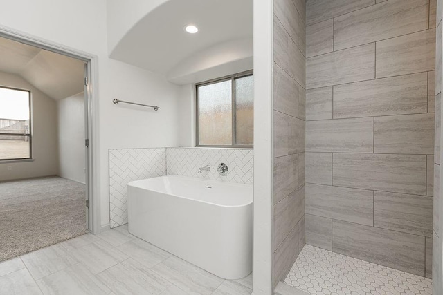 9120 SW 34th St, Oklahoma City, OK 73179 - bathroom with a soaking tub, vaulted ceiling, tile patterned flooring, and tile walls