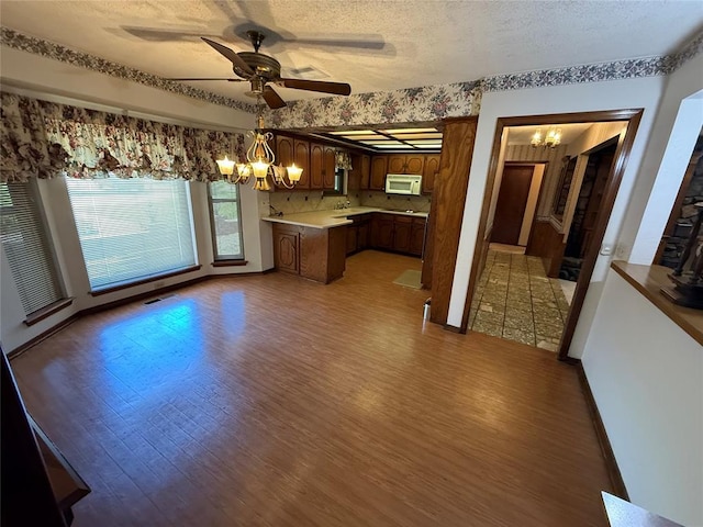 5624 N Mueller Ave, Bethany, OK 73008 - kitchen with a chandelier, white microwave, light wood-type flooring, a textured ceiling, and a ceiling fan