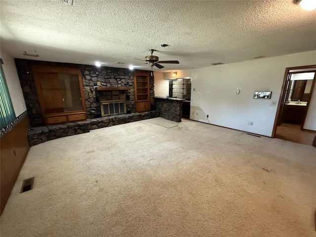 5624 N Mueller Ave, Bethany, OK 73008 - unfurnished living room featuring a fireplace, a ceiling fan, a textured ceiling, and carpet flooring
