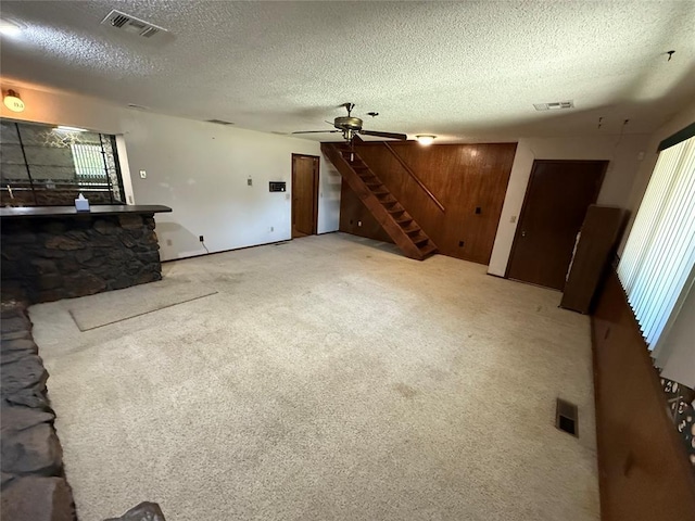 5624 N Mueller Ave, Bethany, OK 73008 - unfurnished living room featuring a textured ceiling, stairs, a ceiling fan, and light carpet