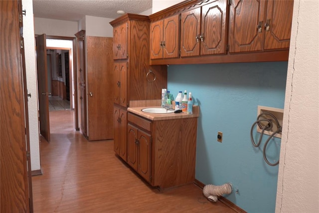 5624 N Mueller Ave, Bethany, OK 73008 - kitchen with brown cabinetry, light wood-style floors, a textured ceiling, and light countertops