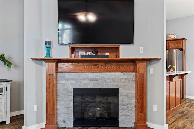4125 Queens Dr, Moore, OK 73160 - detailed view of freestanding refrigerator, baseboards, a glass covered fireplace, and wood finished floors