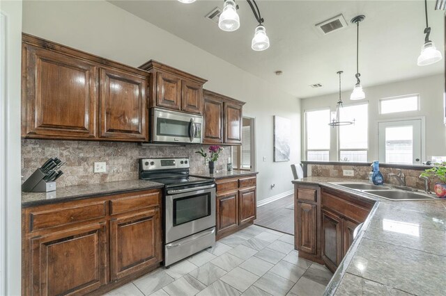 2504 NW 180th St, Edmond, OK 73012 - kitchen with stainless steel appliances, a sink, tasteful backsplash, pendant lighting, and baseboards