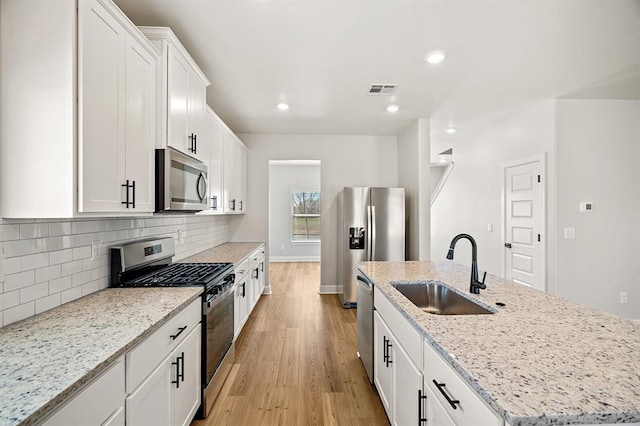 11904 SW 30th St, Yukon, OK 73099 - kitchen featuring appliances with stainless steel finishes, a sink, a kitchen island with sink, light wood finished floors, and tasteful backsplash
