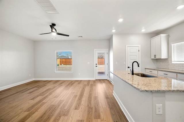 11904 SW 30th St, Yukon, OK 73099 - kitchen with a sink, white cabinets, light wood-style floors, a center island with sink, and plenty of natural light