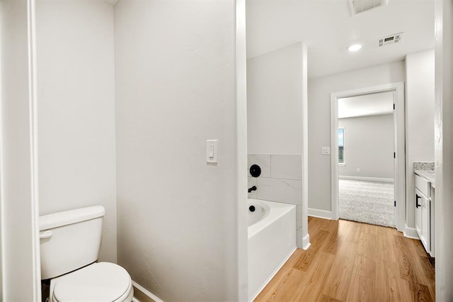 11904 SW 30th St, Yukon, OK 73099 - full bathroom featuring wood finished floors, toilet, a tub to relax in, baseboards, and vanity