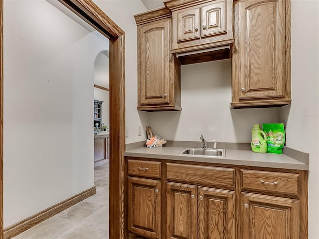 1017 SW 107th St, Oklahoma City, OK 73170 - kitchen with a sink, light countertops, arched walkways, light tile patterned floors, and baseboards