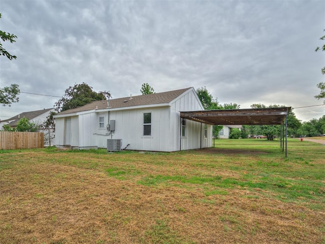 rear view of house featuring board and batten siding, cooling unit, and a carport