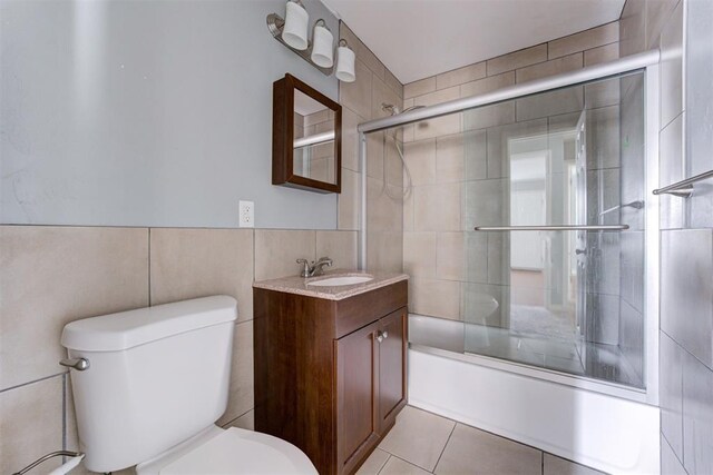 2109 Brighton Ave, Oklahoma City, OK 73120 - bathroom featuring tile walls, toilet, vanity, enclosed tub / shower combo, and tile patterned flooring