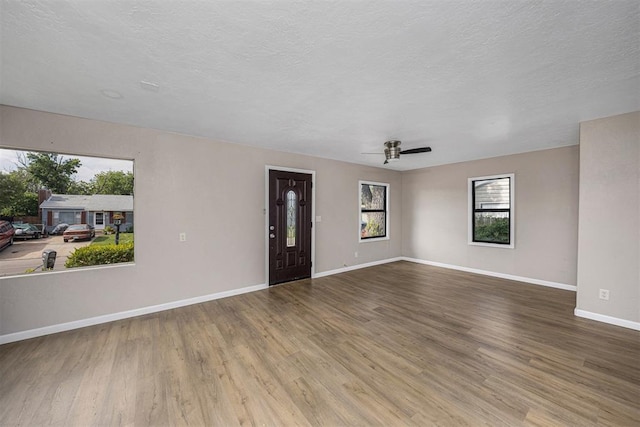 3134 NW Ferris Ave, Lawton, OK 73505 - unfurnished living room featuring wood finished floors, baseboards, a textured ceiling, and ceiling fan