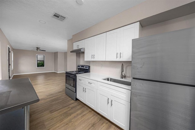 3134 NW Ferris Ave, Lawton, OK 73505 - kitchen featuring appliances with stainless steel finishes, a sink, a ceiling fan, wood finished floors, and white cabinetry