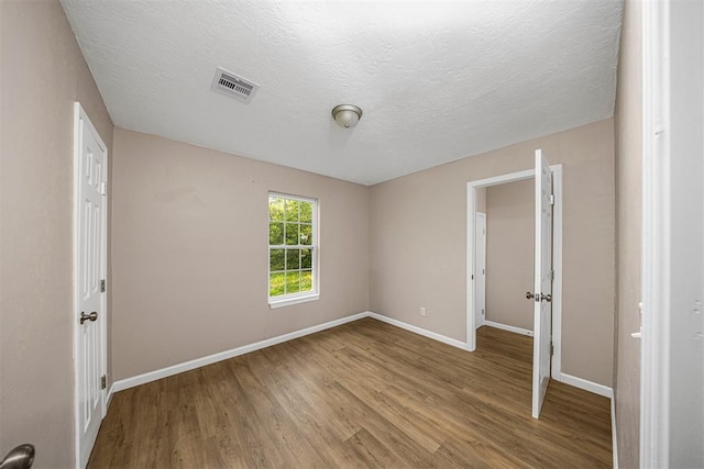 3134 NW Ferris Ave, Lawton, OK 73505 - unfurnished bedroom featuring wood finished floors, baseboards, and a textured ceiling