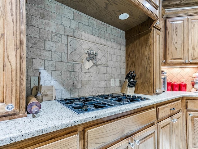 5877 W Washington Ave, Piedmont, OK 73078 - kitchen featuring black gas cooktop, decorative backsplash, and light stone counters
