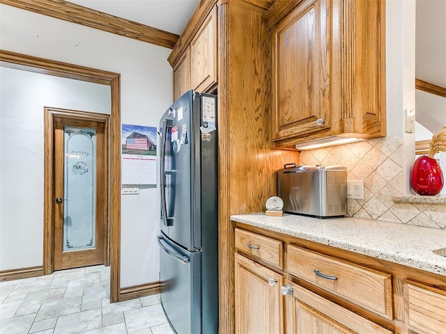 5877 W Washington Ave, Piedmont, OK 73078 - kitchen featuring freestanding refrigerator, tasteful backsplash, light stone countertops, brown cabinetry, and stone finish floors