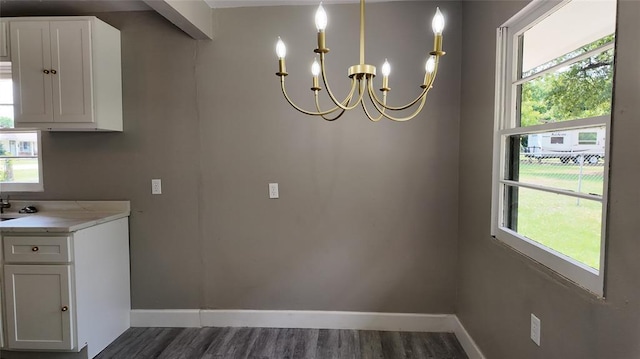 617 Holman Pl, Midwest City, OK 73110 - unfurnished dining area with baseboards, dark wood finished floors, a chandelier, and plenty of natural light
